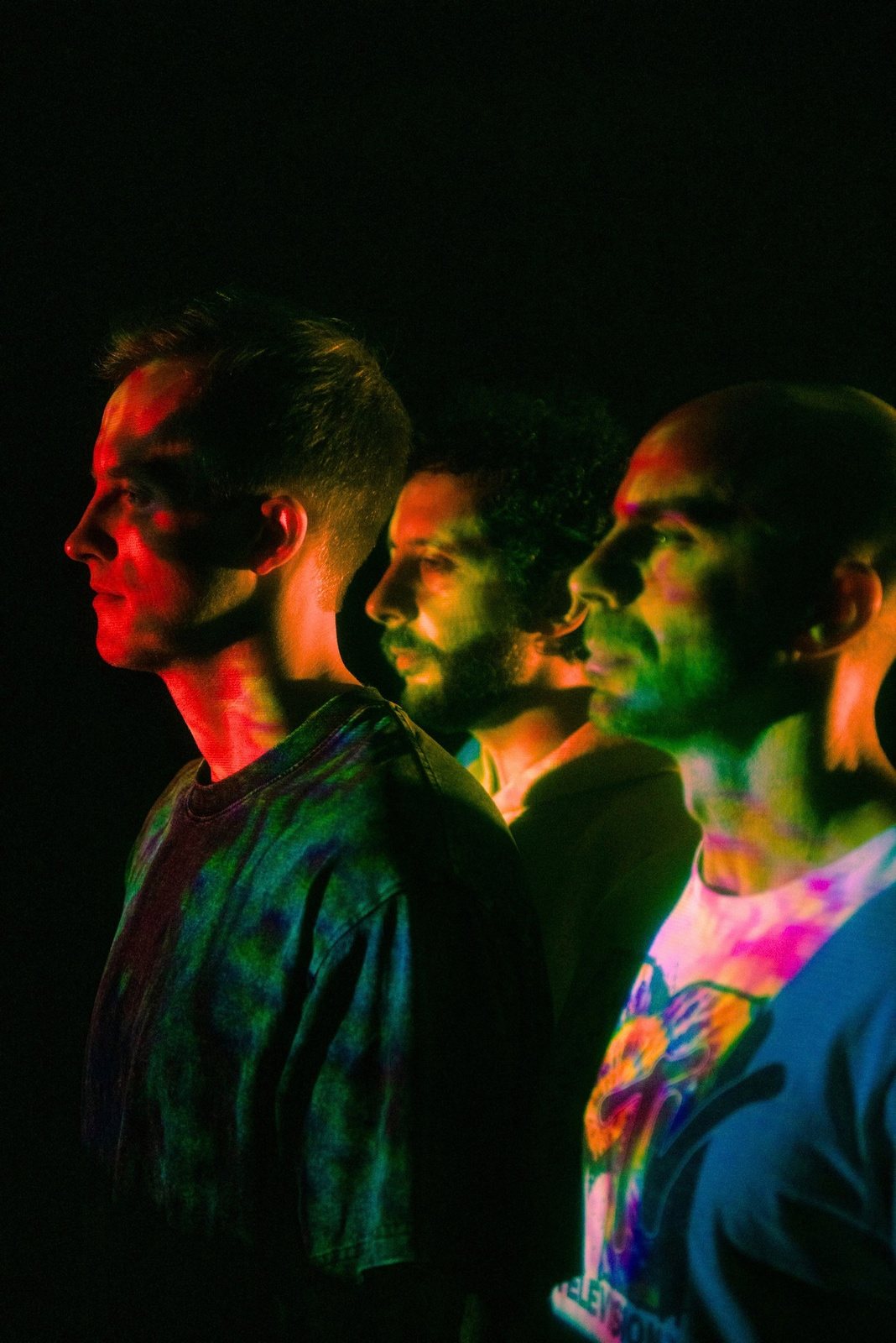 Peter, Mickey and Alex in profile under colored light